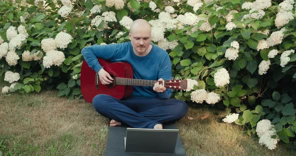 Man in with Guitar in Park Nature is Streaming Online Podcast Using Gadgets alt