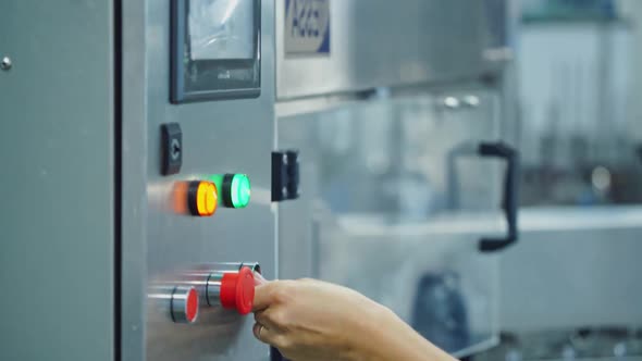 Woman turn on a mechanical machine for milk packaging into bottles alt