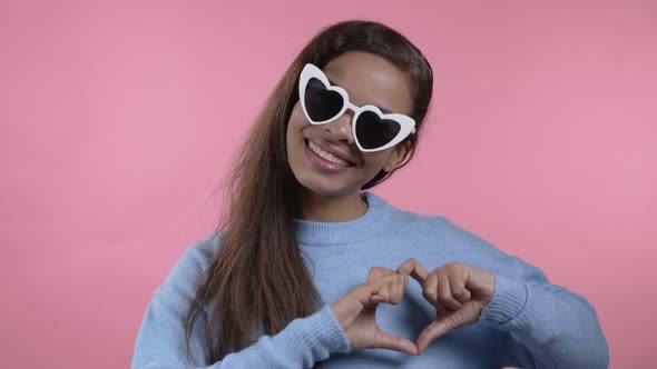 Kind African Woman Making Sign of Shape Heart Near Her Chest alt