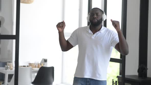Handsome african american man dancing at home using headphones