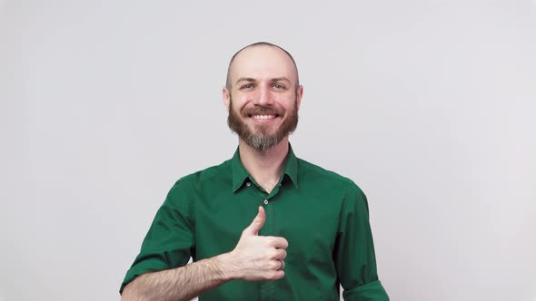 Happy bearded man showing thumbs up sign over white background. Good job.