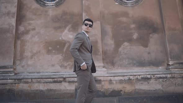 serious businessman walking in suit near modern building. Confident business man in glasses at stree alt