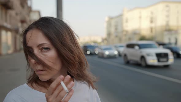 Portrait of a Brunette on a City Street Against the Background of Passing Cars is Out of Focus alt
