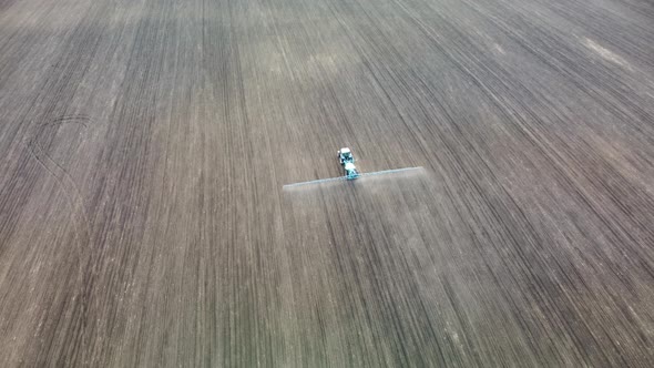 Aerial view tractor spraying seeds on land field