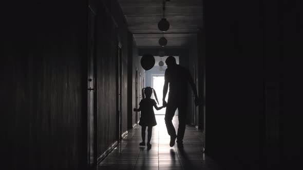 Silhouettes of Dad and Daughter with Balloon Walking along Corridor