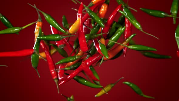 Super Slow Motion Shot of Mixed Chilli Side Colision on Dark Red Background at 1000Fps. alt