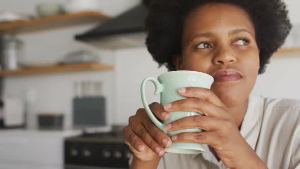 Happy african american woman drinking coffee in kitchen alt
