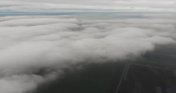 Aerial, tilt, drone shot, above low clouds alt