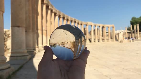 Crystal Ball Reflection Against Ancient Ruins of Roman City, Columns, Hand Holding