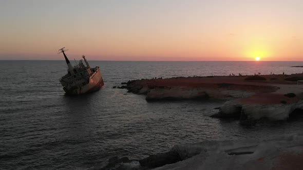 Drone Shot Slowly Moving Up a Shipwreck in the Sea with a Beautiful Pink Sunset