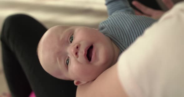 Portrait of Cute Crying Newborn Baby Looking at Camera on Mother's Hands alt