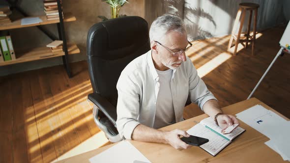 Middleaged Male Holding Credit Card and Entering Its Number Into Smartphone Shopping Online Working alt