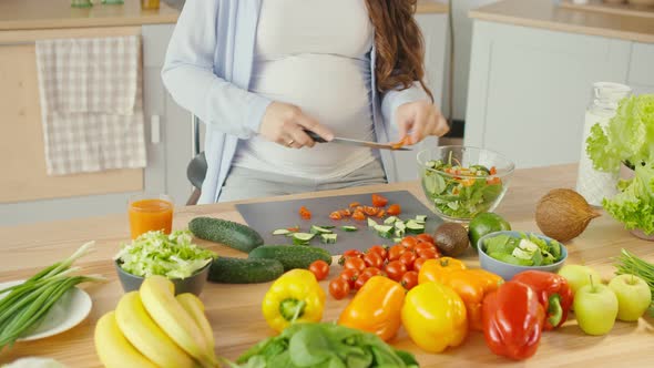 Pregnant Woman in the Kitchen Cuts Tomatoes Prepares Dinner alt
