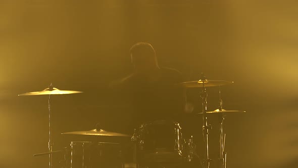 Silhouette Drummer Playing on Drum Kit on Stage in a Dark Studio with Smoke and Neon Lighting alt