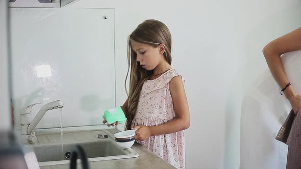 Woman Washing Dishes with Her Daughter