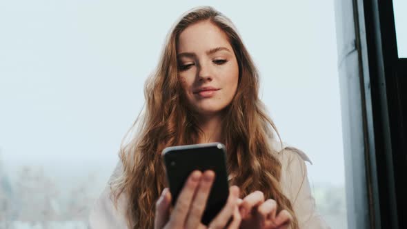 Young Girl With Long Hair Holding Cellphone In Her Hands. alt