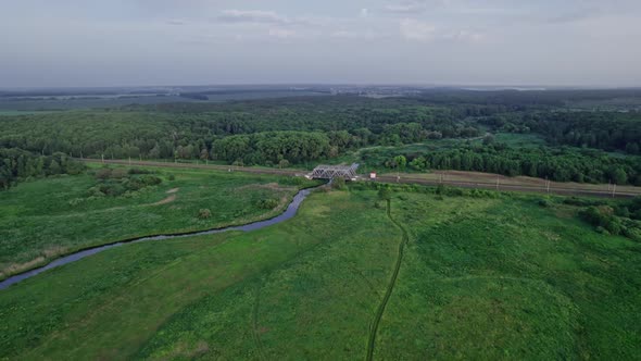 Metal Structure Railway Bridge Over a Small River and the Trees of a Forest alt