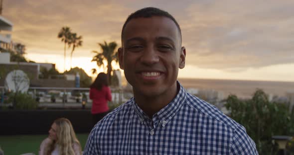 Young African American man smiling at camera on a rooftop alt