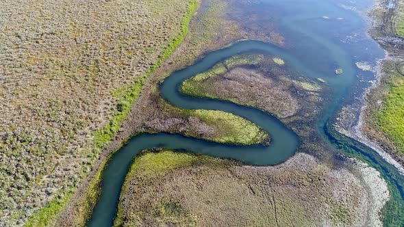 Flying over winding river as it flows into reservoir alt