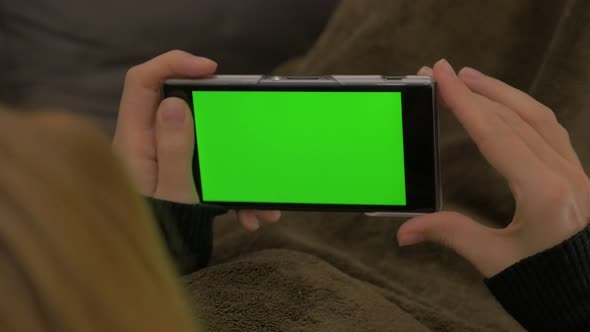 Woman looking at  green screen on smart phone 4K 2160p UHD footage - Chroma greenscreen on mobile ph