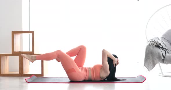 Fitness woman doing abs crunches exercise lying flat on floor training at home.