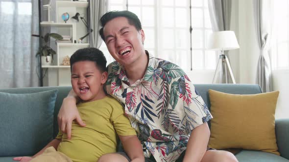 Happy Asian Father And His Son Are Watching Tv At Home. Family Time alt