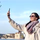 Medium Shot Smiling Elegant Tourist Woman Taking Selfie Using Smartphone on Embankment at Sunset