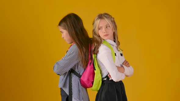 Two schoolgirls in school uniforms with backpacks are not friendly