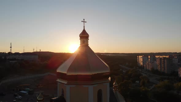 The sun looking out from behind church dome. Aerial shot. Sunset.