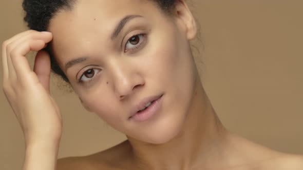 Beauty Portrait of Young African American Woman Looking in Mirror Touching Face and Correcting Hair alt