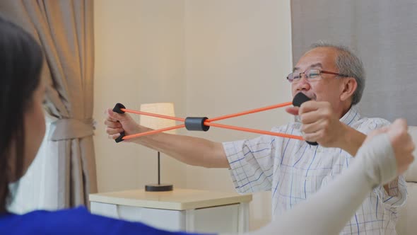 Asian Disabled senior man doing physiotherapist using resistance stretch band exercise for health. alt