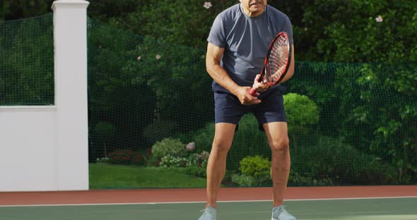 Video of focused of biracial senior man playing tennis on tennis court alt