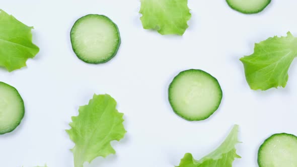 Rotating Vegetable Background of Lettuce Leaves Cucumber Slices on a White Background