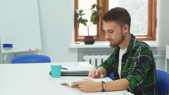 Young Student Is Reading a Book and Drinking Coffee alt