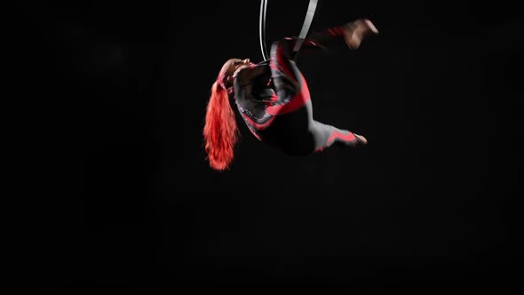 Slim Young Woman Hanging on Air Hoop Doing Delilah Trick in Slow Motion at Black Background alt