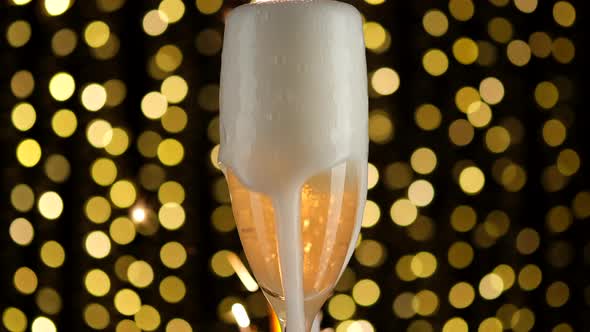Pouring champagne into a glass against a background of fireworks and golden shining lights alt