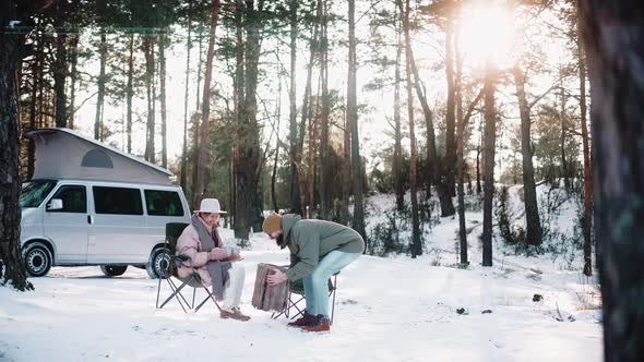 Couple of Travellers Resting in the Woods on Sunny Winter Day Enjoying Van Life