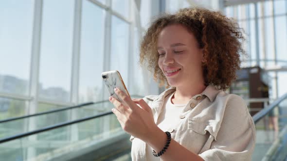 Girl Uses Mobile As Moves Down From Escalator alt