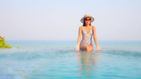 Young asian woman enjoy around outdoor swimming pool for leisure alt