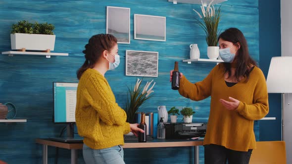 Friends with Face Masks Clinking Bottles of Beer at New Normal Party alt