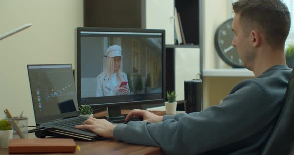 Man Videographer Edits and Cuts Footage and Sound on His Personal Computer with Two Monitors. alt