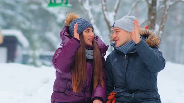 Positive Couple in Warm Jackets Give Five in Snowy City Park