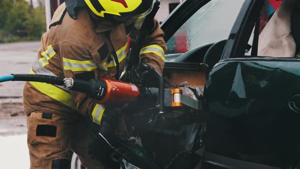 Fireman Cutting Car Door Open at Scene of Car Accident. Slow Motion alt