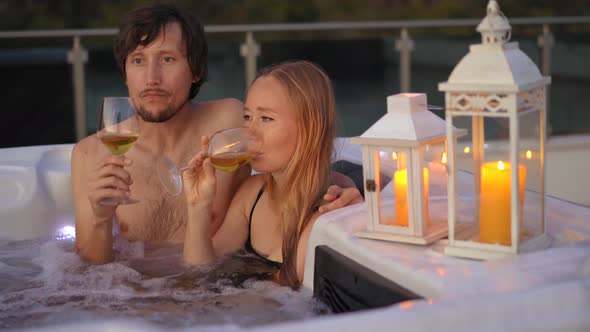 A Young Man and Woman are Relaxing in the Hot Tub on a Rooftop with a View on Mountains During alt