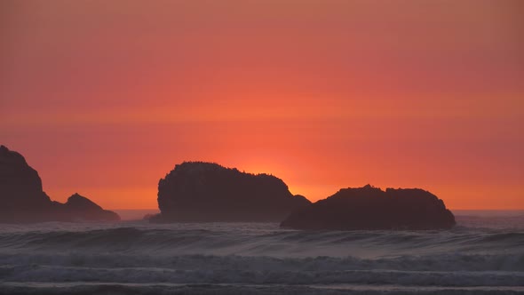 A rock with a large flock of birds casts a silhouette in front of the fading sunset light at an Oreg alt