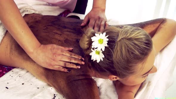 Relaxed Woman Lying on Spa Bed for Body Scrubbing Massage Using Traditional Herb alt