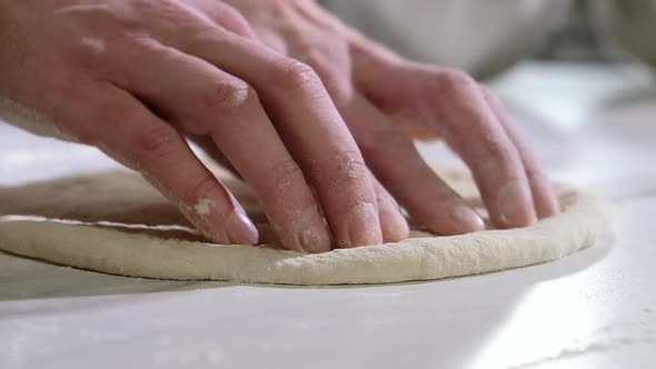 Professional baker prepares dough for traditional Italian pizza.