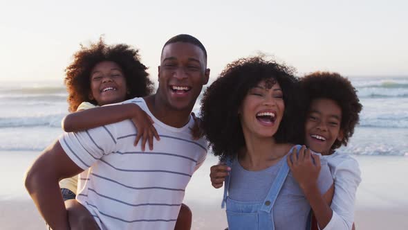 Portrait of african american family smiling together at the beach alt