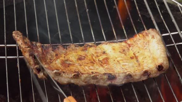 Delicious Ribs are Rotated on the Grill Grid on the Background of the Open Fire alt