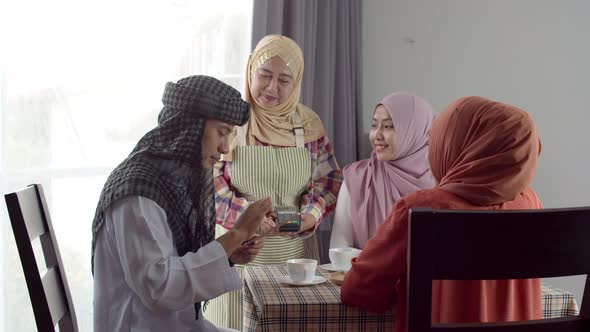 Young muslim man use smartphone contactless payment in coffee shop alt